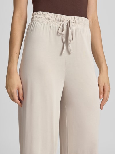 Frauenmodel trägt Weite Hose aus Viskose-Mix Modell 'ANORA' von PIECES in Beige, glatte Textur, lockerer Schnitt, Nahaufnahme Oberkörper. Damen Weite Hose von PIECES.