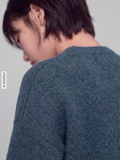 Kobieta modelka ma na sobie Oversized Pullover mit Woll-Anteil Modell 'BOOM' od VERO MODA, miękka tekstura, kolor niebieskoszary, zbliżenie na plecy, KI-modifiziertes Bild