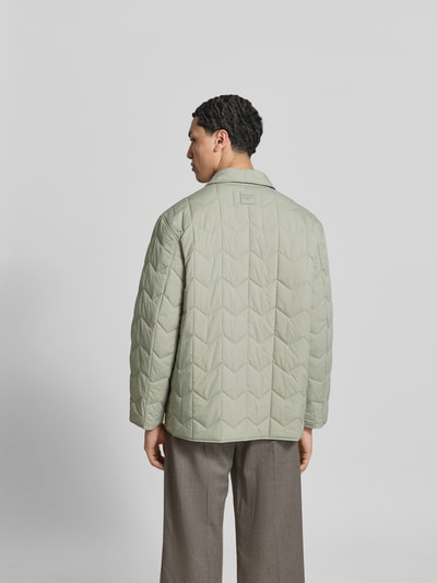 Männermodel trägt Regular Fit Jacke in Stepp-Optik von MAISON KITSUNÉ in hellem Grün, geradlinige Stepp-Nähte, Ganzkörperansicht Rückansicht, Umlegekragen, Pattentaschen, durchgängige Knopfleiste, Rückenlänge bei Größe M 75 cm, Schulterbreite 48 cm, Ärmellänge 62 cm.