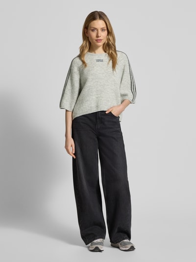 Vrouwenmodel draagt Cropped Strickpullover met geribbelde boorden model 'VITOW' van American Vintage, wol-alpaca-mix, losse fit, grijs, label-stitching, cropped, ronde hals, vooraanzicht full body.