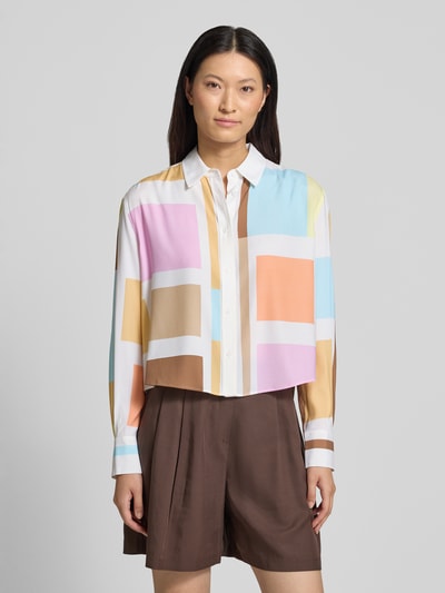 Modelka nosi Boxy Fit Bluse im Allover-Look od HERZENS, mieszanka materiałów z dodatkiem streczu, kołnierzyk koszulowy, listwa guzikowa, długość tyłu 59 cm, długość rękawów 61 cm, kolorowe geometryczne kształty o gładkiej fakturze, Ganzkörperansicht von vorne.