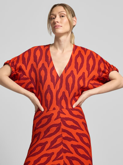 Kobiece model prezentuje A-Linien Freizeitkleid mit V-Ausschnitt Modell 'KOMFORTABLE' von Essentiel Antwerp, czerwony wzór, tekstura żakardowa, dekolt w serek, sukienki casualowe, zbliżenie na górną część ciała