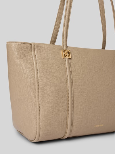 Produktfoto, Shopper mit Label-Detail von CK Calvin Klein in Beige, strukturierte Oberfläche, goldene Details, Tragehenkel sichtbar, Damen Shopper, Reißverschluss-Hauptfach, Innenfach mit Reißverschluss, Maße: 48x27x16 cm, Schulterriemen 63 cm.