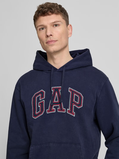 Mannelijk model draagt Hoodie met Logo en Känguru-Tasche van GAP in donkerblauw, katoenmix, regular fit, logo, kangoeroezak, bovenlichaam close-up.