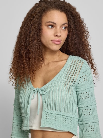 Frauenmodel trägt Regular Fit Strickjacke aus Baumwoll-Mix Modell 'NATALIE' von Only, Optik: Unifarben, Schnürung, Trompetenärmel, Ajour-Strick, Nahaufnahme Oberkörper.