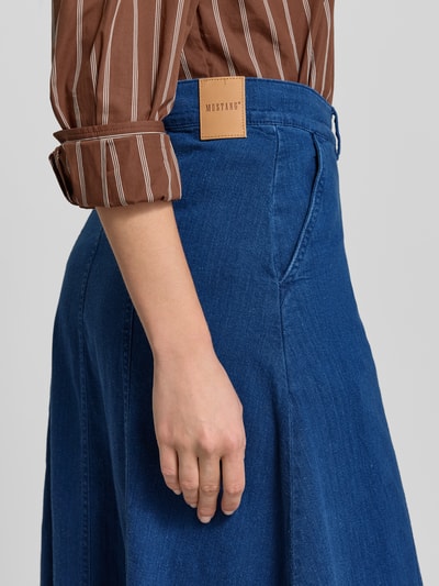 Kobiece modelka nosi spódnicę midi z tkaniny stylizowanej na denim, model 'Ally' od Mustang, wpuszczane kieszenie, listwa guzikowa, bawełna, linia a, szerokość w rozmiarze 27: 38 cm, całkowita długość w rozmiarze 27: 81 cm, detaliczne ujęcie boczne.