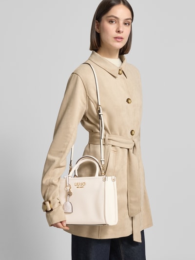 Frauenmodel trägt Tote Bag mit Logo-Applikation Modell 'Ridhi' von Liu Jo White in Beige, mit Hauptfach, Reißverschluss, Tragehenkel und abnehmbarem Schulterriemen, Ganzkörperansicht von vorne.