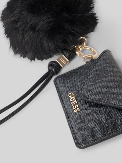 Produktfoto, Schlüsselanhänger mit Bommel Modell 'YVONNE' von GUESS, Logo-Muster, Label-Detail, schwarze strukturierte Oberfläche, Damen Accessoire