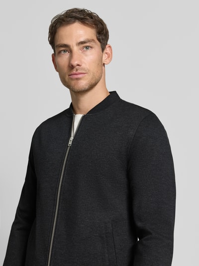 Männermodel trägt Slim Fit Sweatjacke mit Stehkragen von Lindbergh, Mieszanka materiałów z dodatkiem streczu, zamek błyskawiczny, wpuszczane kieszenie, długość tyłu w rozmiarze M: 67 cm, długość rękawów w rozmiarze M: 66 cm, kolor ciemnoszary, krój slim fit, Ganzkörperansicht von vorne