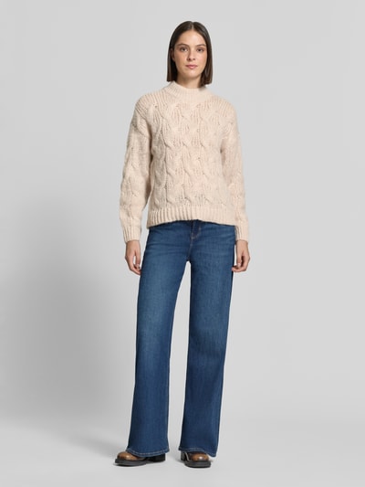 Frauenmodel trägt cremefarbenen Regular Fit Pullover mit Rundhalsausschnitt Modell 'MAYBE' von VERO MODA, grobe Strickstruktur, Ganzkörperansicht von vorne.