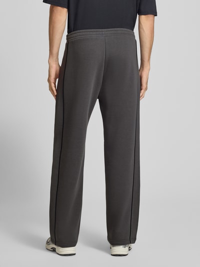 Männermodel trägt Straight Fit Sweatpants aus reiner Baumwolle mit Label-Patch von REVIEW, dunkelgrau, elastischer Bund, Eingrifftaschen, Ganzkörperansicht Rückansicht.