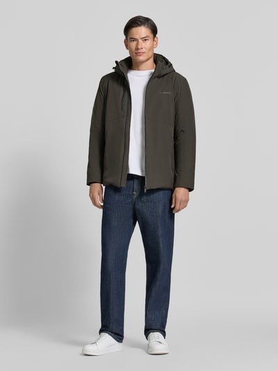 Männermodel trägt Regular Fit Jacke mit Logo-Print von Lindbergh aus elastyczna mieszanka materiałów, kaptur z tunel, nadruk z logo, Napoleonkieszeń, dł. tyłu w rozm. M 74 cm, szerokość ramion w rozm. M 46 cm, szerokość klatki piersiowej w rozm. M 42 cm, długość rękawów w rozm. M 62 cm, kolor ciemny khaki, prosta faktura, całkowity widok z przodu