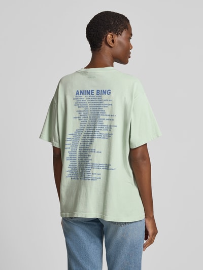 Frauenmodel trägt Oversized T-Shirt mit Logo-Print von Anine Bing aus reiner Baumwolle, Oversized-Fit, Rückansicht, Rückenlänge 62 cm, hellgrün-blau.