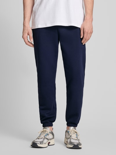 Männermodel trägt Sweatpants mit Logo und elastischem Bund von GAP aus Baumwoll-Mix, Regular-Fit, dunkelblau, Ganzkörperansicht von vorne.