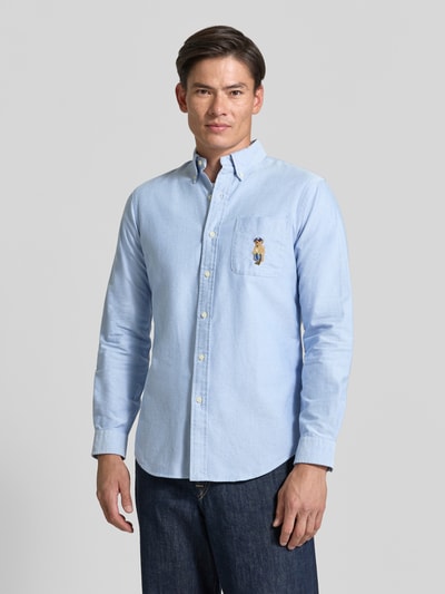 Männermodel trägt Custom Fit Freizeithemd aus reiner Baumwolle von Polo Ralph Lauren in Hellblau, glatte Textur, Ganzkörperansicht von vorne.
