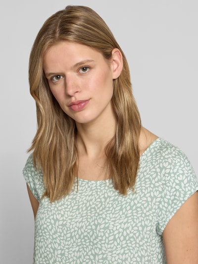 Kobiece modelka nosi Regular Fit Blusenshirt aus reiner Viskose Modell 'NOVA' od Only, jasny wzór liści, okrągły dekolt, krótki rękaw, miękka faktura, krój regular fit, całkowicie z przodu zbliżenie górnej części ciała.