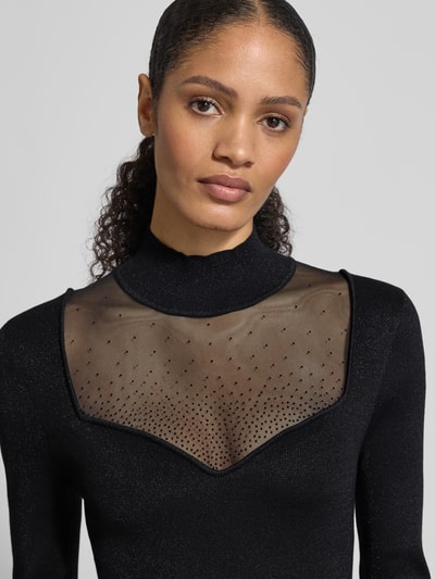 Frauenmodel trägt Slim Fit Kleid aus Viskose-Mix mit Ziersteinbesatz Modell 'Lucy' von Guess, semitransparent, Langarm, Nahaufnahme Oberkörper.