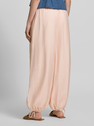 Frauenmodel trägt Relaxed Fit Stoffhose aus Viskose-Mix von Gina Tricot, semitransparentes Design, elastischer Bund mit Tunnelzug, eingefasste Ärmelabschlüsse, Bundweite bei Größe S: 39 cm, Innenbeinlänge bei Größe S: 73 cm, Ganzkörperansicht Rückansicht.