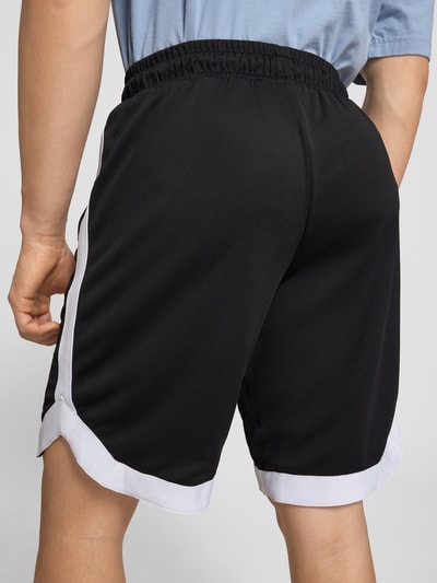 Männermodel trägt Relaxed Fit Shorts mit elastischem Bund von Pegador, schwarze Struktur, weißer Saum, Logo-Stitching, Rückansicht