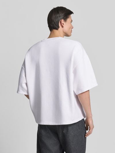 Männermodel trägt T-Shirt mit Logo Modell 'PLIZZY' von American Vintage in Weiß, Baumwolle, Relaxed Fit, Ganzkörperansicht Rückansicht.