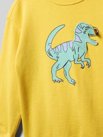 Mädchen trägt Regular Fit Sweatshirt mit Allover-Motiv-Print von Blue Seven, gelb, Reine Baumwolle, Rundhalsausschnitt, elastische Abschlüsse, Nahaufnahme Oberkörper.