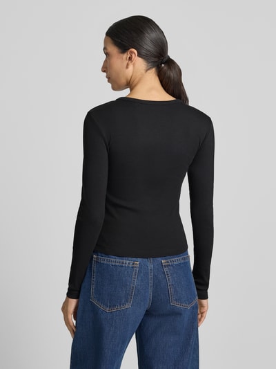 Frauenmodel trägt schwarzes Slim Fit Langarmshirt aus Baumwoll-Mix Modell 'CHLOE' von VERO MODA, glatte Stoffstruktur, Ganzkörperansicht Rückansicht.