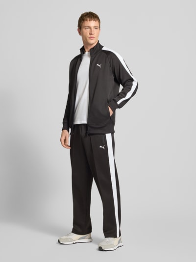 Männermodel trägt schwarze Straight Fit Sweatpants mit Logo-Stitching Modell 'Always On' von PUMA PERFORMANCE, Material-Mix, Ziernähte, elastischer Bund, Reißverschluss-Eingrifftaschen, Ganzkörperansicht von vorne.