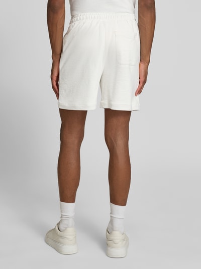 Männermodel trägt Regular Fit Sweatshorts aus reiner Baumwolle von Lacoste, unifarben, Logo-Stitching, elastischer Bund, Ganzkörperansicht Rückansicht.