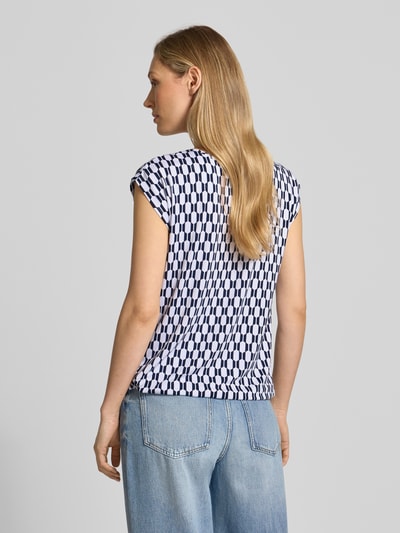 Vrouwenmodel draagt Blusenshirt mit Rundhalsausschnitt van ZABAIONE in wit-blauw patroon, rechte fit, viscose-elastaanmix, korte mouwen, ruglengte 58 cm, totaalbeeld rugaanzicht.