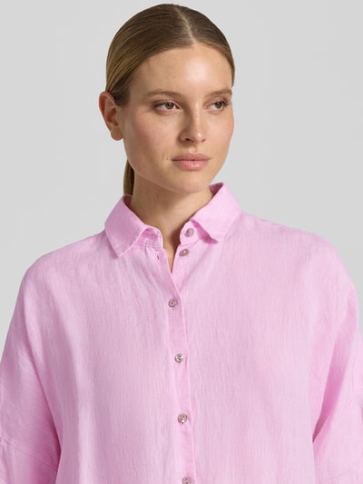 Frauenmodel trägt Leinenbluse mit überschnittenen Schultern von Christian Berg Woman in Rosa, strukturierte Oberfläche, Nahaufnahme Oberkörper.
