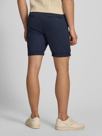 Mężczyznamodel nosi Regular Fit Shorts mit Münztasche od Superdry, mieszanka bawełny, krój regular fit, kieszonka na monety, kieszenie z tyłu, zapięcie na guzik i zamek błyskawiczny, szerokość w rozmiarze 32: 44 cm, długość wewnętrzna nogawki w rozmiarze 32: 20 cm, granatowy kolor, gładka faktura, widok całej sylwetki od tyłu