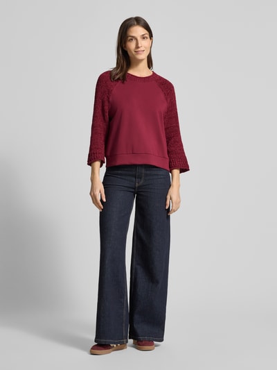 Frauenmodel trägt Relaxed Fit Pullover mit Strick-Besatz von Marc Cain in Dunkelrot, Baumwoll-Mix, Jeans, Ganzkörperansicht von vorne.
