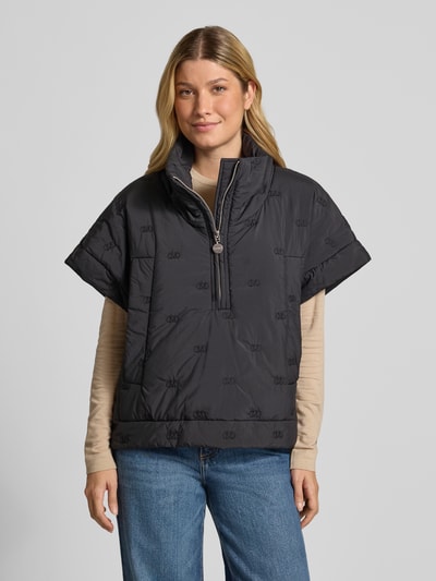 Vrouwenmodel draagt Cape met rits en steekzakken model 'NETTI' van Cph Muse in zwart, regular fit, staande kraag, voorkant bovenlichaam close-up, ruglengte 61 cm, borstwijdte 64 cm, context: dames cape