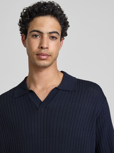 Männermodel trägt Relaxed Fit Poloshirt aus Viskose-Mix Modell 'FLINT' von Only & Sons, Farbe Dunkelblau, Struktur, Nahaufnahme Oberkörper. Optik: Unifarben, Passform: Relaxed-Fit, Muster: Struktur, Polokragen, V-Ausschnitt, Kurzarm, Ärmelabschluss: Gerippt, Rumpfabschluss: Gerippt, Material: Viskose-Mix.