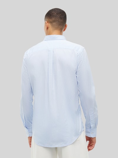 Männermodel trägt Body Fit Freizeithemd aus reiner Baumwolle von Tommy Hilfiger in Hellblau mit feinen Streifen, Ganzkörperansicht Rückansicht.