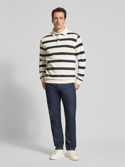 Männermodel trägt Relaxed Fit Poloshirt mit Streifenmuster von Lindbergh, Baumwoll-Mix, dunkelblau-weiße Streifen, Ganzkörperansicht von vorne.