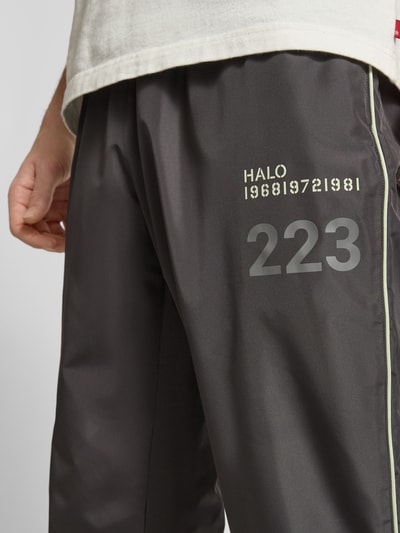 Männermodel trägt Trainingshose mit elastischem Bund von HALO, Relaxed-Fit, Label-Print, Reißverschlusstaschen, Nahaufnahme Oberschenkel.