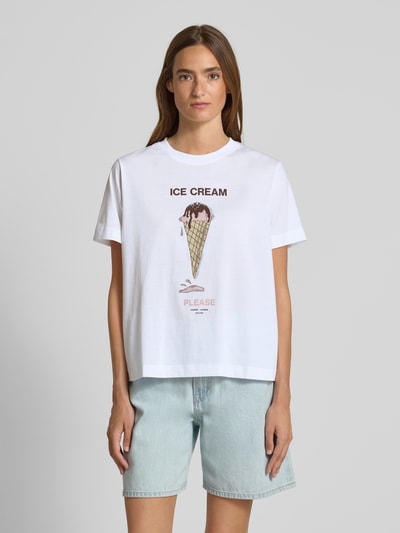 Frauenmodel trägt T-Shirt mit Motiv-Print Modell 'CAMINO' von Samsøe Samsøe, weiße Baumwolle, lockerer Schnitt, Rundhals, Motiv Eiscreme, Ganzkörperansicht von vorne.