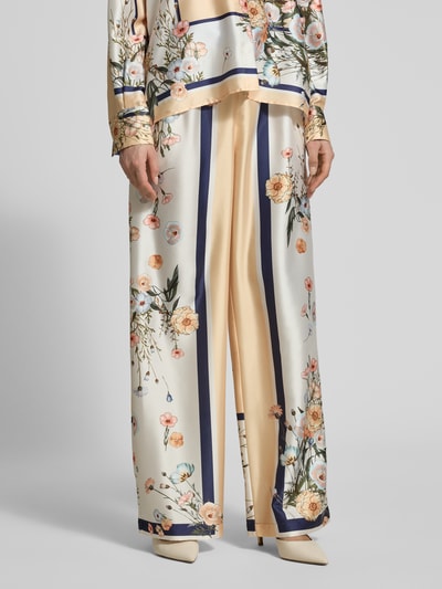 Frauenmodel trägt Wide Fit Stoffhose aus Satin von Liu Jo White mit floralem Allover-Print, elatischem Bund und Tunnelzug, Nahaufnahme Unterkörper.