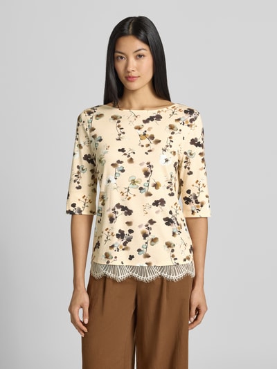 Frauenmodel trägt Regular Fit Bluse aus Baumwoll-Mix mit Spitzenbesatz von Marc Cain, floraler Allover-Print, 1/2-Arm, Ganzkörperansicht von vorne.