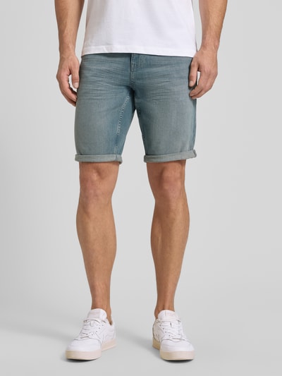 Męski model nosi Regular Fit Jeans Bermudas aus Baumwoll-Mix von Tom Tailor, stylizowana na denim, krój regular fit, mieszanka bawełny, 5 kieszeni, naszywka z logo, jasnoniebieski, zapięcie na guzik i zamek błyskawiczny, szlufki na pasek, widok na nogi, z przodu, zbliżenie na dolną część ciała.