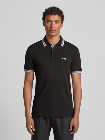 Männermodel trägt Regular Fit Poloshirt mit Label-Stitching Modell 'Paddy' von BOSS aus reiner Baumwolle, Ganzkörperansicht von vorne.
