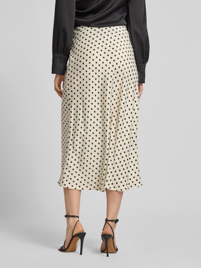 Vrouwenmodel draagt Midirock met zijrits model 'PELLA' van YAS, rechte fit, stretch-materiaalmix, crème met zwarte stippen, volledige achteraanzicht.