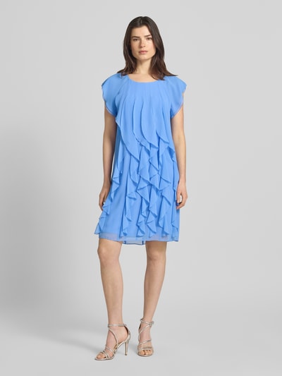 Modelka kobieca nosi Relaxed Fit Minikleid mit Allover-Rüschenbesatz od Vera Mont, okrągły dekolt, kryta halka, rękawy typu cap, długość tyłu w rozmiarze 36: 90 cm, szerokość w rozmiarze 36: 39 cm, jasnoniebieski kolor, lekka falista tekstura materiału, widok całej sylwetki z przodu.