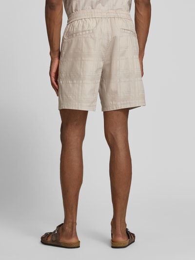 Männermodel trägt Tapered Chinoshorts aus reiner Baumwolle Modell 'SANDREW_6_SHORTS' von BOSS Orange, Optik: Unifarben, Struktur, Tunnelzug, Bundabschluss: elastisch, Beinabschluss: mit Seitenschlitz, Ganzkörperansicht Rückansicht.