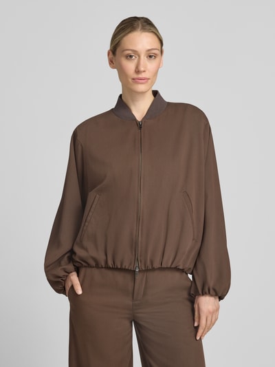 Frauenmodel trägt Blouson aus Lyocell-Mix mit Zweiwege-Reißverschluss von Drykorn in Braun mit Stehkragen, Eingrifftaschen, Relaxed-Fit, Nahaufnahme Oberkörper, Rückenlänge 55 cm, Brustweite 74 cm, Ärmellänge 60 cm, Modell SOWLEY, Größe 36.