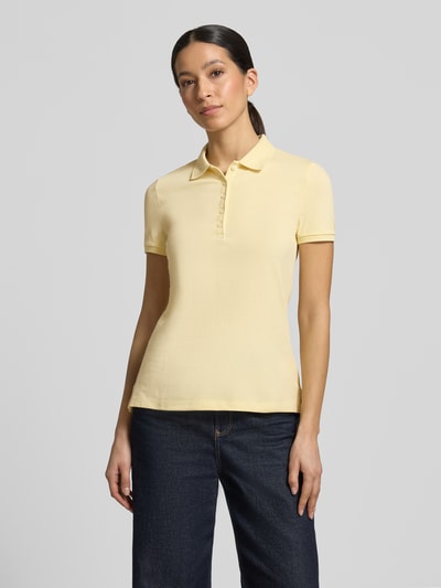 Frauenmodel trägt Slim Fit Poloshirt mit Knopfleiste von Christian Berg Woman, Baumwoll-Elasthan-Mix, zartgelb, Seitenschlitze, Rückenlänge 62 cm, Ganzkörperansicht von vorne.