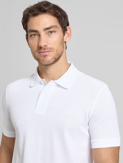 Mężczyzna nosi Regular Fit Poloshirt aus reiner Baumwolle Modell 'PALLAS' von BOSS, biały, krój regular fit, pikowana bawełna, krótkie rękawy, widok z przodu, zbliżenie na górną część ciała.