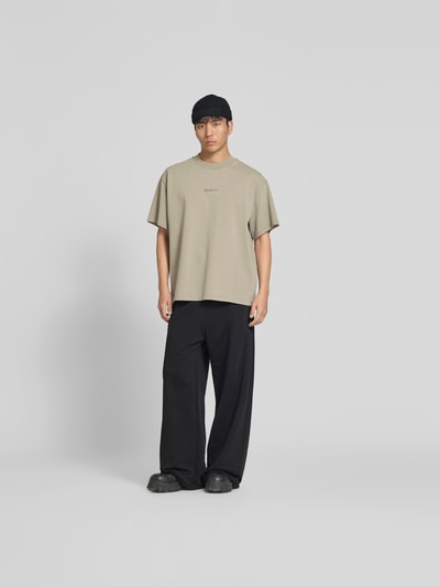 Männermodel trägt Relaxed Fit T-Shirt mit Logo-Stitching von WON HUNDRED aus reiner Baumwolle, sandfarben, Ganzkörperansicht von vorne.