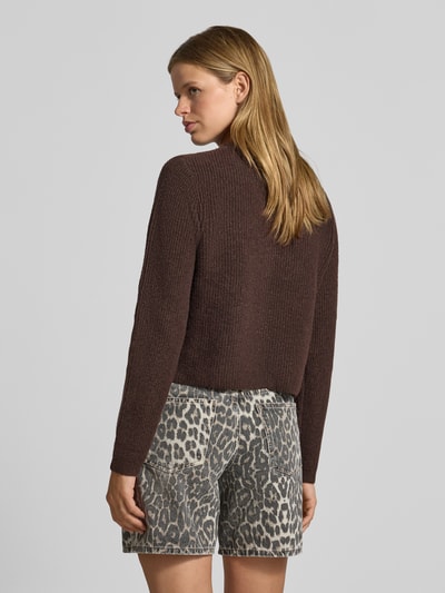 Frauenmodel trägt Strickjacke mit Woll-Anteil Modell 'SILLY' von PIECES in Dunkelbraun zu gemusterten Shorts, Ganzkörperansicht Rückansicht.
